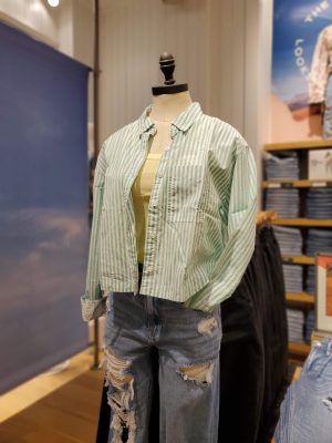 Mannequin wearing a green button down shirt and ripped jeans