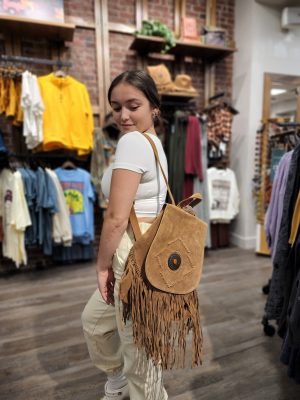 Young Woman with a brown leather fringed backpack on her shoulder 